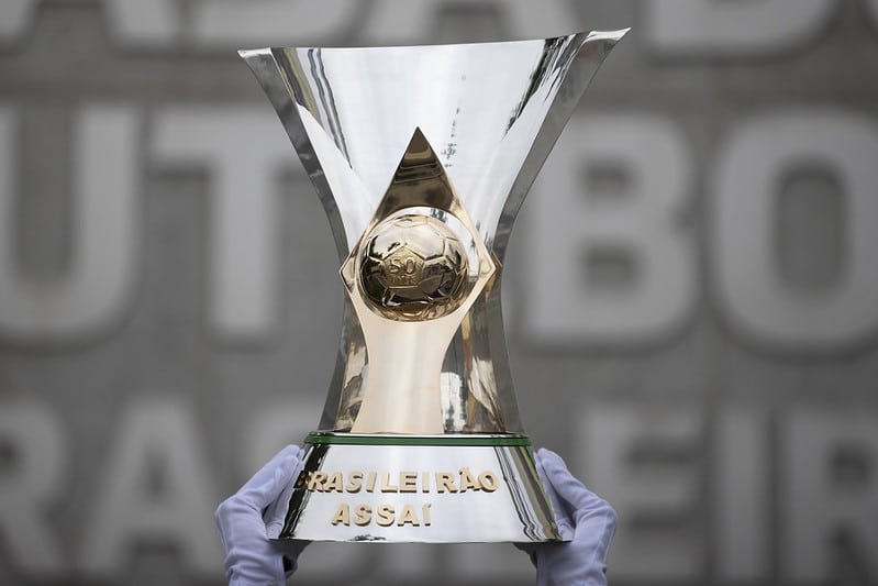 Taça do Brasileirão erguida por duas mãos de luva