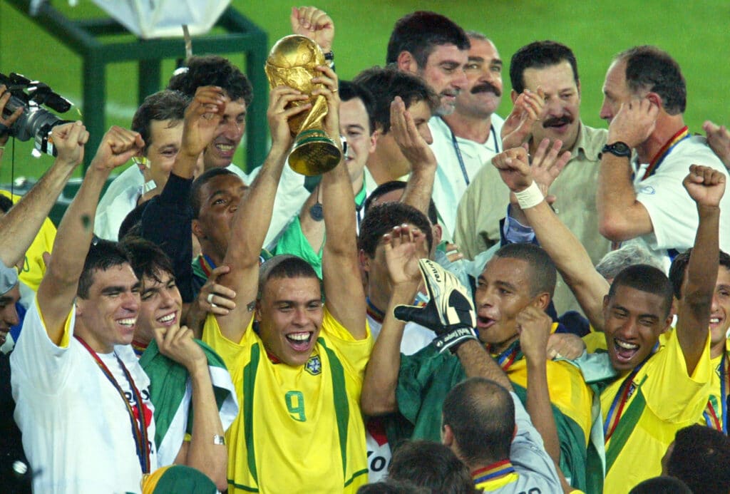 Ronaldo Fenômeno erguendo taça da Copa do Mundo de 2002, rodeado pelos companheiros da Seleção Brasileira, após vitória do Brasil na final