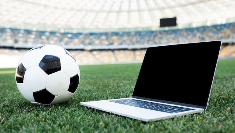 Notebook em estádio de futebol com uma bola ao lado